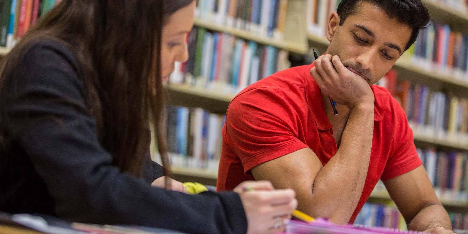 Two students study something written in a notebook.
